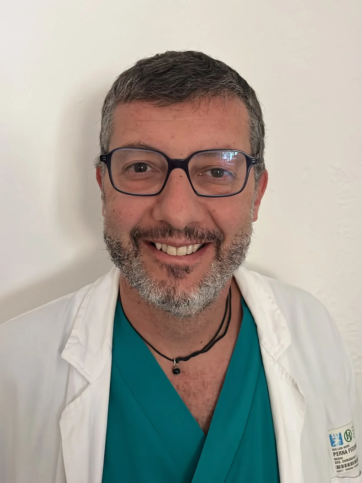 Federico Perna in camice bianco e divisa chirurgica.